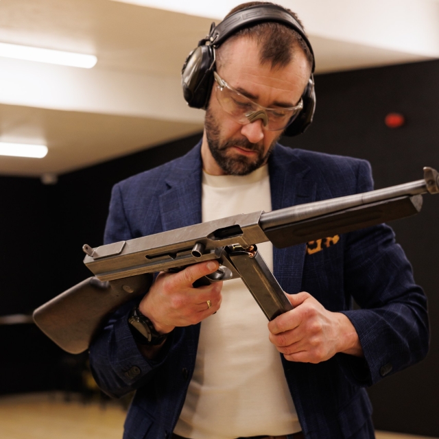 Man in a smoking holding a Thompson